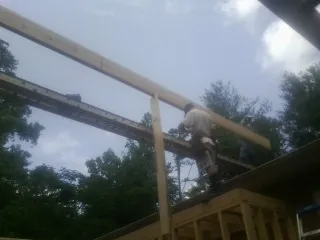 Carpenter setting a ridge beam over a new addition frame — Ice Dam Removal by Roofing Brothers in Blissfield