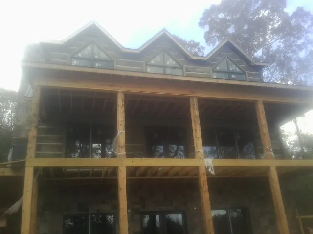 Dormers and porch framing on a large log home under construction — Roof Coating work by our crew in Blissfield