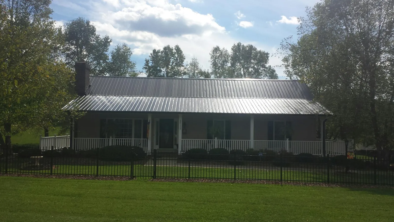Gray metal roof on a brick ranch with a full width front porch — Gutter Guard Installation work by our crew in Blissfield