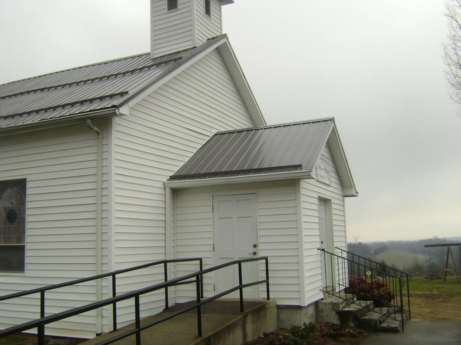 Gray metal roof on a white clapboard church with a steeple in Blissfield