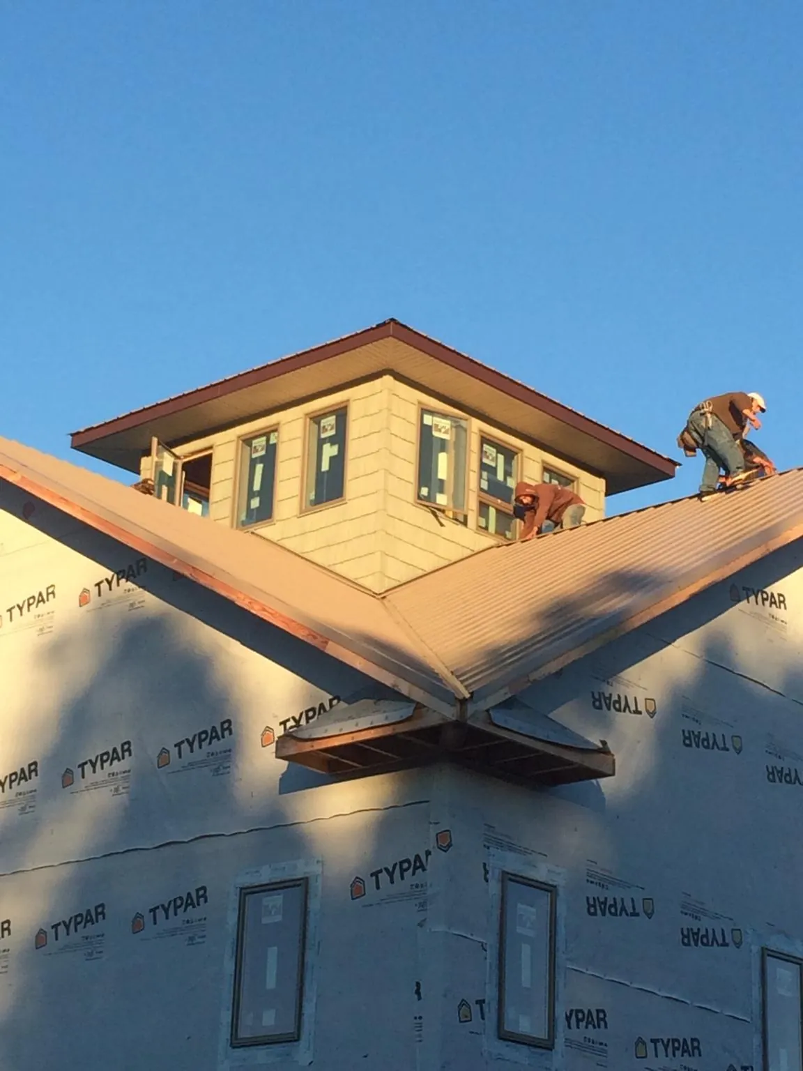 Roofers working around a rooftop cupola on a new metal roof at sunset — Roof Waterproofing in Blissfield by Roofing Brothers